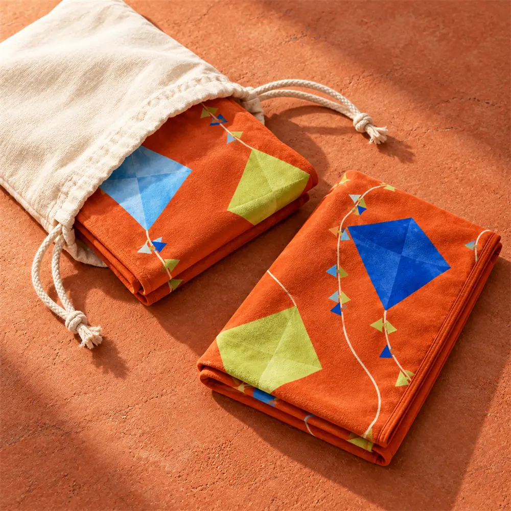 YJ-310 optional drawstring pouch Folded orange kite-print towel beside a natural-color drawstring pouch on a terracotta surface