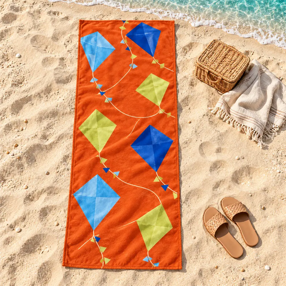 YJ-310 beach picnic scene Orange geometric kite-print towel laid on sand beside a beach picnic basket and sandals